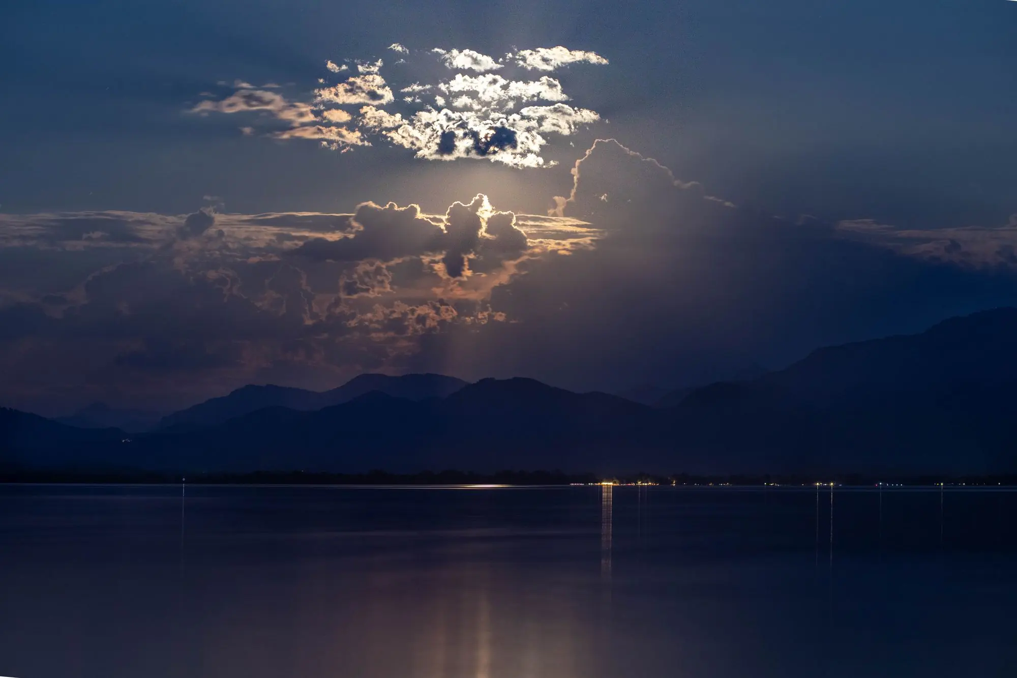 Moonlight over a still mountain lake at night